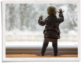 孩子摸着窗户嵌在外面有雪的窗户上