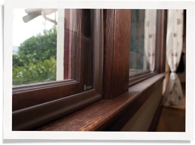 带有棕色框架的窗户插件的特写图像与木窗框匹配。