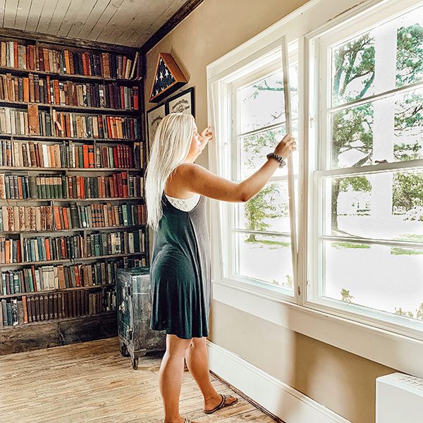 一位妇女在书架旁安装窗套以减少噪音