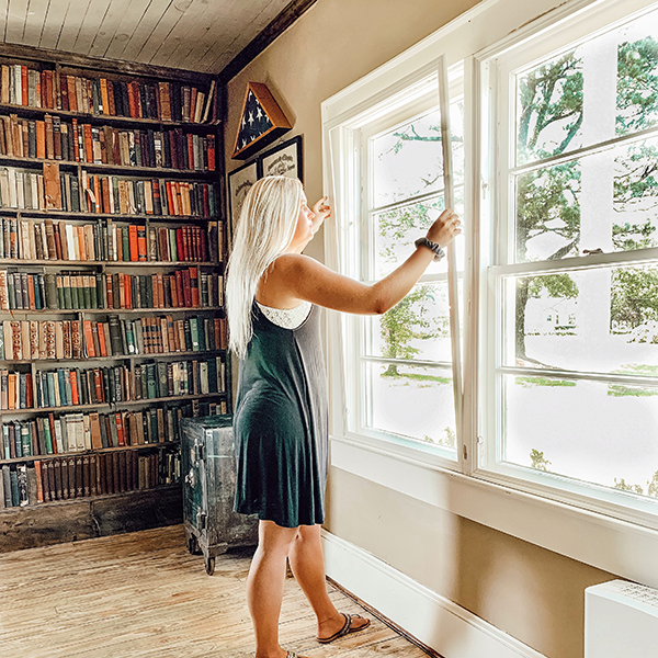 女人安装拍下窗口插入以减少书架旁边的噪音