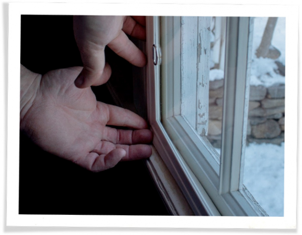 A person touching their window frames in order to check for a window leak.