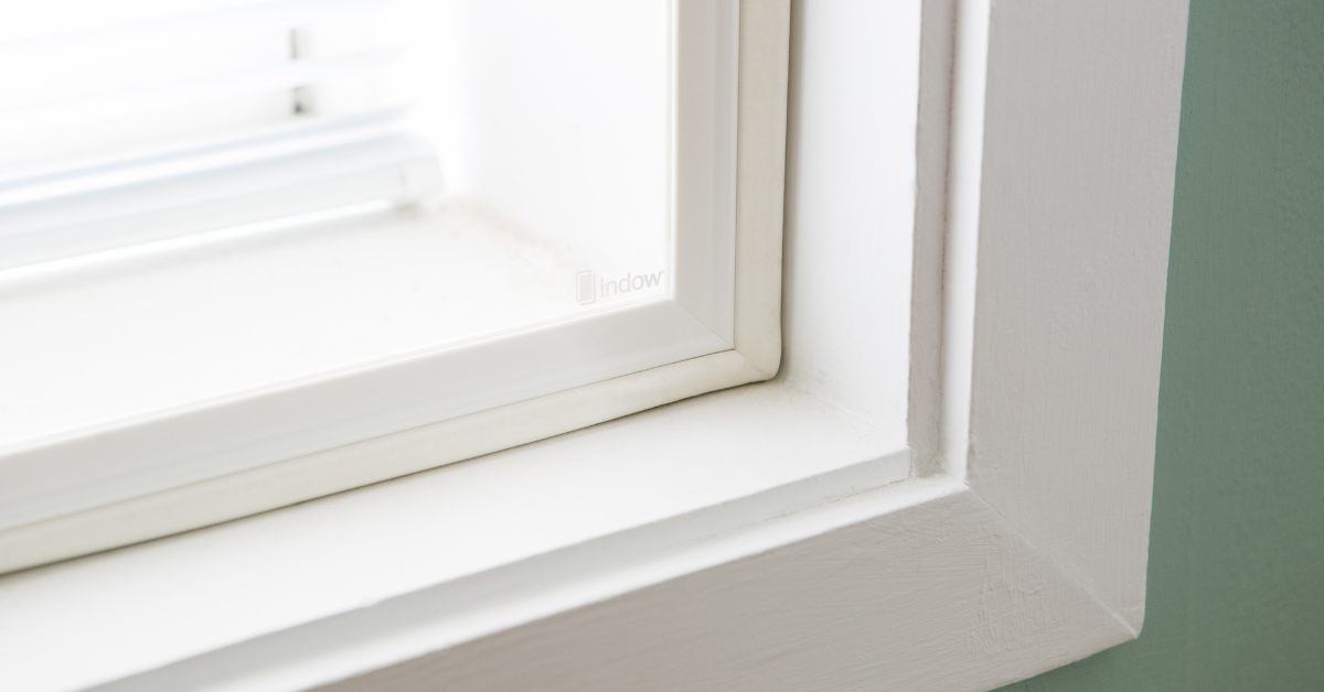 A white window frame with an Indow window insert.
