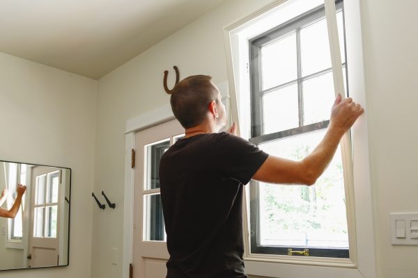 一个人正在将大窗口插入到房屋的窗户中。